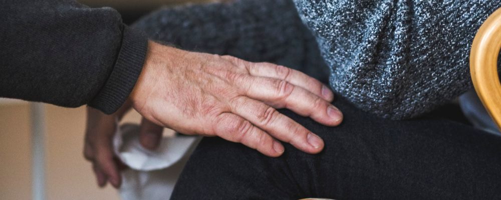 Närbild hand på knä. Foto.