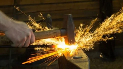 Slägga som slår på ett städ och gnistorna flyger