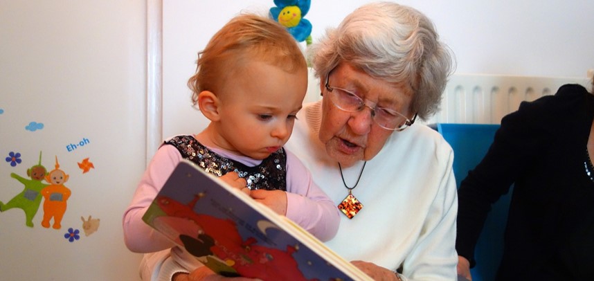 &Auml;ldre kvinna l&auml;ser tillsammans med liten flicka.